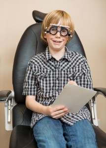 7701947-boy-with-trial-frame-holding-test-chart-at-optician